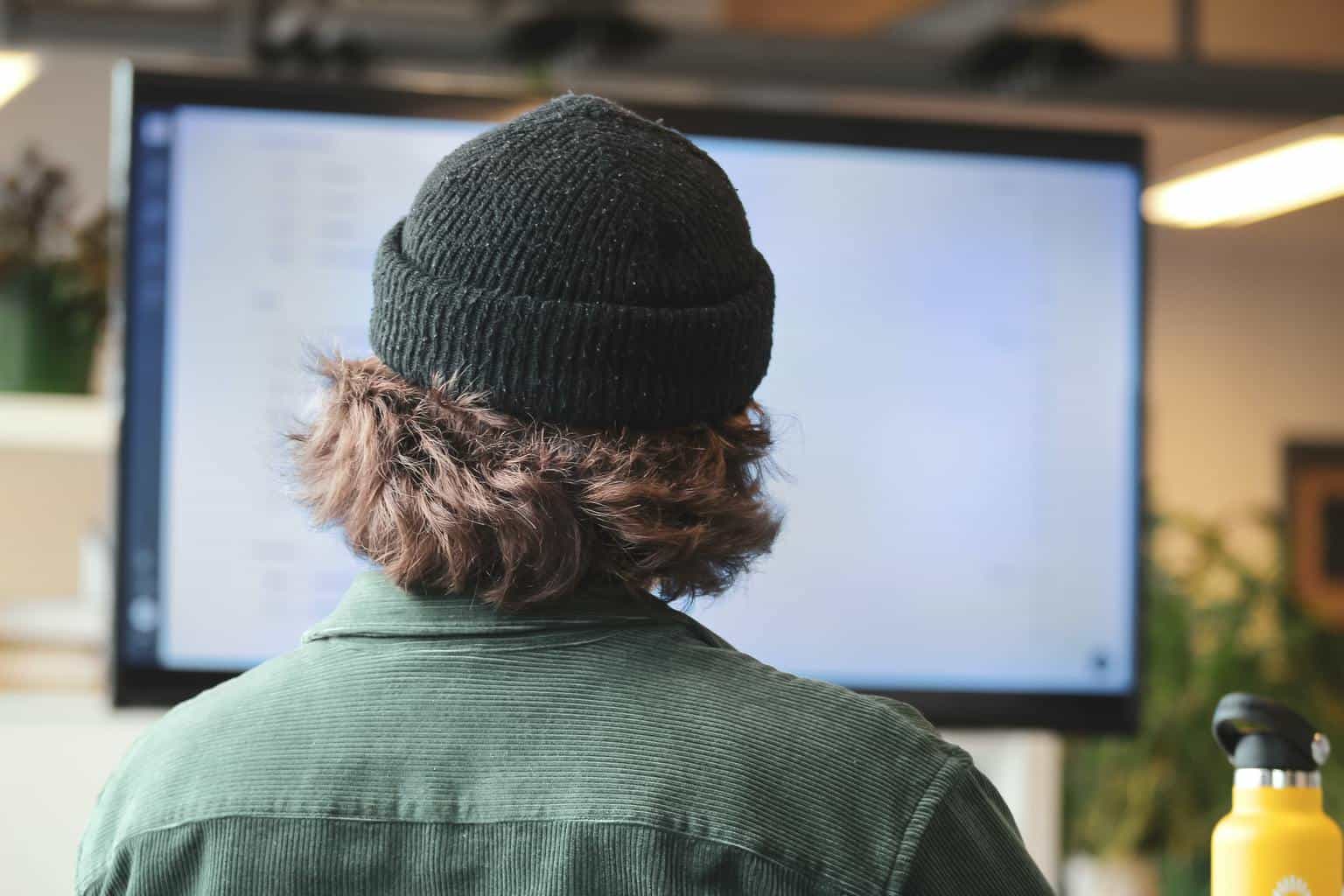 Man wearing beanie looking at screen